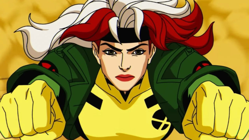 Cena da série animada X-Men '97Na imagem, a personagem Vampira está em primeiro plano, com os braços esticados para a frente de punhos fechados, enquanto voa. Ela é uma mulher de pele clara, olhos verdes e cabelos ruivos com mechas brancas. Ele usa uma faixa preta na testa, luvas amarelas e jaquetas verdes. Por dentro, usa um uniforme amarelo com detalhes pretos nos peitos e o símbolo de X dos X-Men 