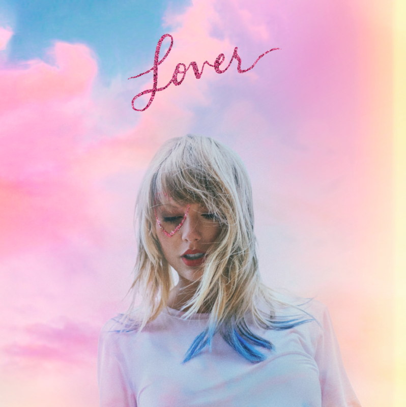 Imagem da capa do álbum Lover de Taylor Swift. Taylor está vestindo uma camiseta branca, com mechas azuis em seu cabelo loiro. Ela tem um desenho de coração em glitter rosa ao redor de um dos olhos. O fundo é um céu com nuvens em tons de rosa, roxo e azul. A palavra Lover está escrita em glitter rosa no topo da imagem.