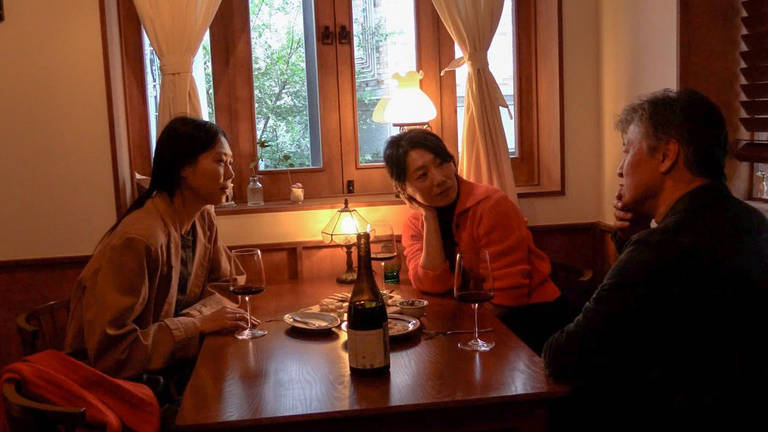 O cenário é uma mesa de um restaurante. Três personagens estão em cena. Na direita está o personagem de Kwon Hae-hyo com uma roupa preta e com a mão no queixo. Na esquerda está Kim Min-hee com uma roupa cor de bege. No centro está Jo Yun-hee com uma blusa rosa. As duas olham para o personagem de Kwon Hae-hyo. Existem três taças na mesa na frente de cada um. Eles estão bebendo alguma bebida alcoólica.