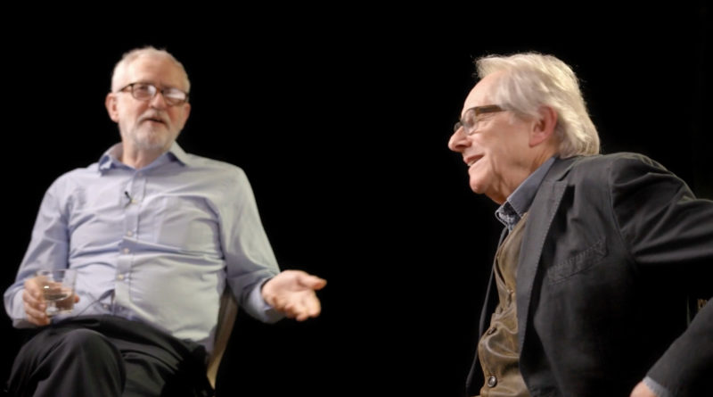 Imagem do documentário Maus Patriotas. Na foto, o político Jeremy Corbyn e o cineasta Ken Loach, dois homens brancos, estão sentados em um estúdio e dão entrevistas; O homem da esquerda usa uma camisa social azul, uma calça preta e o da direita usa uma blusa marrom com uma jaqueta preta.