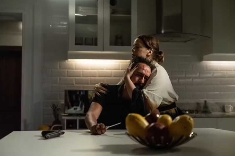 O cenário é uma cozinha. Na cena, Valério está sentado com um canivete na mão, chorando, e com a cabeça deitada no peito de Regina. Ele veste uma camisa preta. Regina segura a cabeça de Valério contra o seu peito. Ela está com uma roupa branca manchada nas mangas.