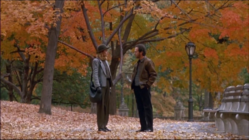 Cena de Harry e Sally : Feitos um para o outro mostra duas pessoas conversando em um parque durante o outono. A esquerda, temos uma mulher, Sally,  vestida com um chapéu cinza, casaco cinza claro e calça larga, com uma bolsa pendurada no ombro. Já a direita, temos um homem o Harry, que usa uma jaqueta marrom e calças escuras. Ambos estão cercados por árvores com folhas alaranjadas e amarelas, e o chão está coberto por uma camada de folhas caídas. Ao lado deles, há um banco de parque e um poste de luz antigo, criando uma atmosfera de outono