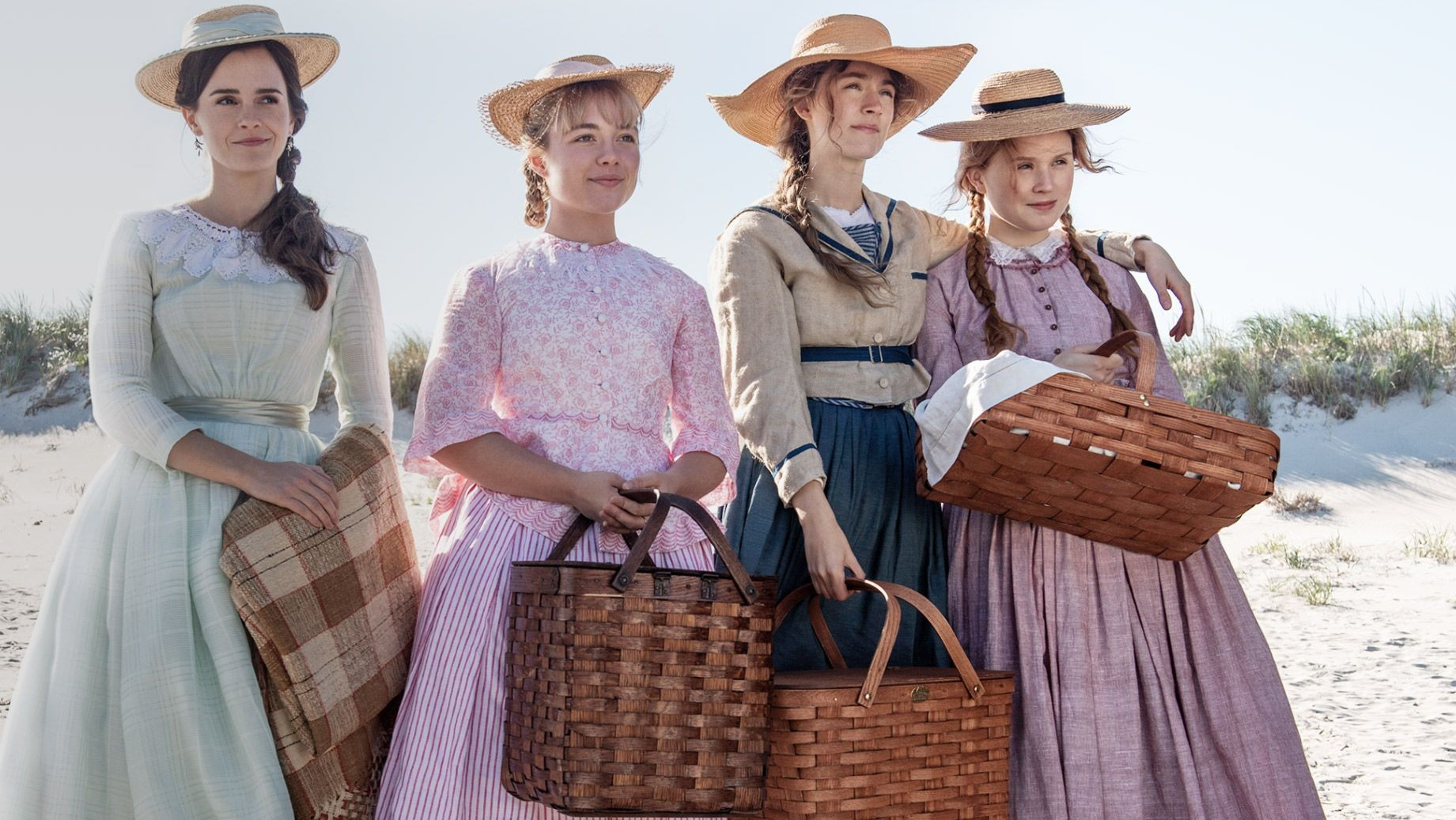 Cena do filme Adoráveis Mulheres. Na imagem, há quatro mulheres brancas em uma praia. Da esquerda para a direita, há uma mulher branca de cabelos castanhos escuros utilizando um vestido verde e segurando uma toalha de mesa, há uma mulher branca de cabelos loiros usando um vestido rosa e com uma cesta, há uma mulher branca de cabelos ruivos segurando uma cesta e utilizando um vestido azul com uma blusa bege por cima e uma mulher branca de cabelos ruivos com vestido rosa com uma cesta. 