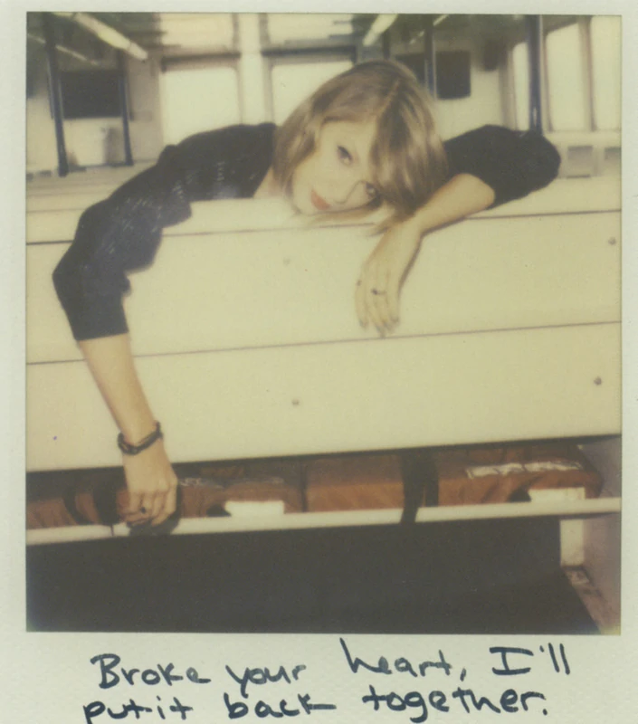 Uma foto polaroid mostrando Taylor Swift, apoiada em uma estrutura branca, olhando diretamente para a câmera com um ar introspectivo. Na parte inferior da imagem, há a frase manuscrita: "Broke your heart, I'll put it back together."