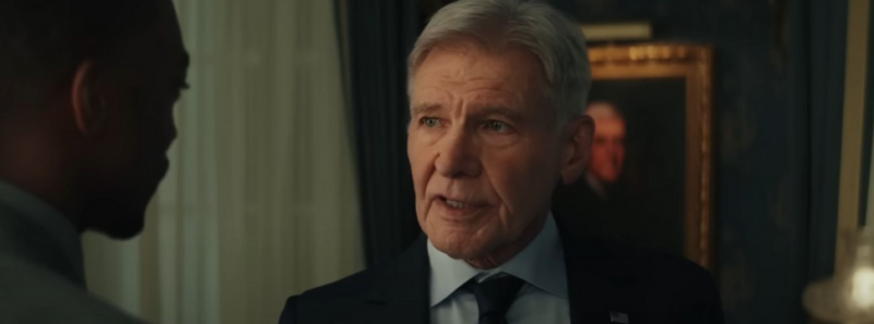 Cena do filme Capitão América: Admirável Mundo NovoNa imagem, à direita, está o personagem Presidente Ross. Ele é um homem branco, de cabelos brancos, na faixa dos 80 anos de idade. Vestindo terno e gravata azul marinho. Atrás dele, há um quadro pendurado na parede. É o retrato de um dos presidentes dos Estados Unidos. Ross está conversando com Sam Wilson, que está de costas. Wilson veste um terno cinza.Ele  é um homem negro, na faixa dos 40 anos e de cabelo raspado, O ambiente é uma sala com paredes escuras e cortina branca.
