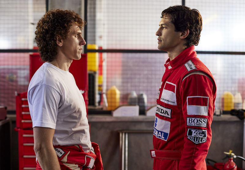 Cena dentro dos boxes da McLaren, os atores de Alain Prost, homem branco de cabelo enrolado e francês e Ayrton Senna, branco cabelo pelo ondulado e macacão vermelho, encenam um momento tenso se encarando após falas acusatórias de ambos os personagens, ambos vestidos com o uniforme de pilotagem da equipe britânica.