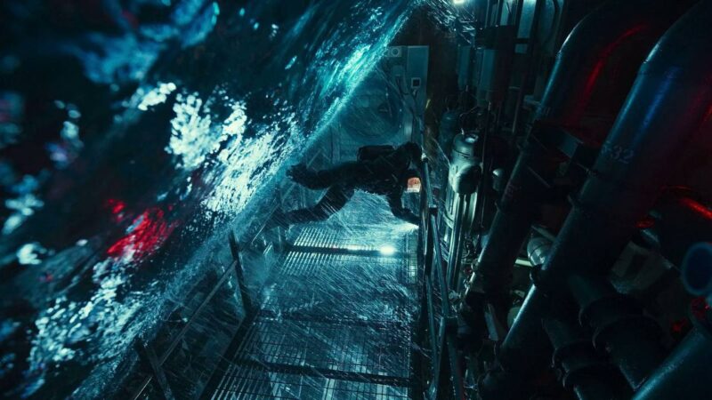 Cena do filme Missão: Impossível - O Acerto FinalNa imagem, Ethan Hunt em um traje preto de mergulho, se equilibra em uma plataforma dentro de um submarino abandonado. Há muita água e ferragens. As cores são sombrias, com tons de azul, preto e vermelho.