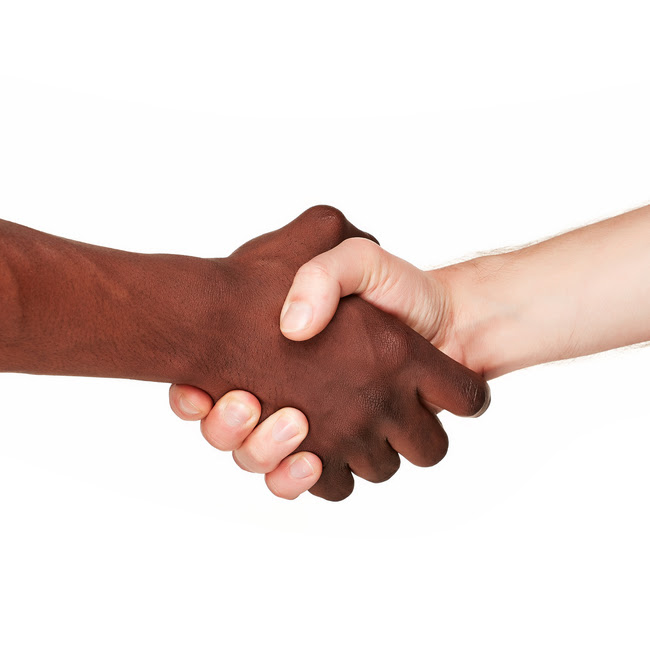 Aperto de mão entre duas pessoas, uma de pele preta e outra de pele branca, com fundo branco.
