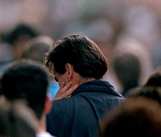 Cena do filme DarkmanNo GIF, o ator Bruce Campbell está de cabeça baixa, com uma das mãos no rosto. Então, ele se vira e olha para trás, em direção à câmera. Campbell é um homem branco, na faixa dos 30 anos, de cabelo preto, liso, com franja. Ele veste uma jaqueta azul. O cenário é uma rua, há muitas pessoas andando. 