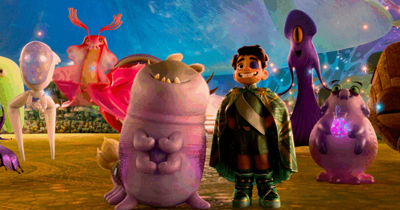 Cena do filme ElioNa imagem, Elio está com as mãos na cintura, vestindo um traje verde, que inclui uma capa, além de um tapa olho no olho esquerdo. Aparecem também alguns membros do planeta Comuniverso - todos coloridos e com formatos peculiares - além de Glordon,um alien sorridente, com dentes afiados e corpo arredondado.