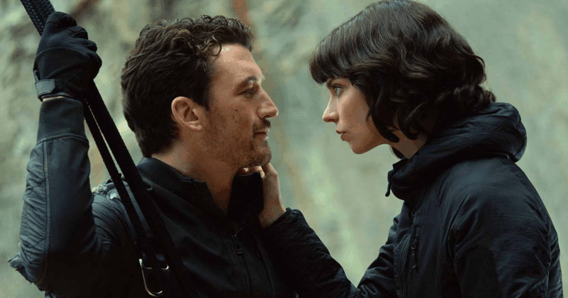 Cena do filme Entre MontanhasNa imagem, Levi (à esquerda) e Drasa (à direita) se despedem. Ela está com a mão direita no rosto dele, enquanto se observam. Levi está segurando uma corda na cor preta, ambos vestem casacos de frio também desta cor. O dia está claro e ao fundo há rochas, em desfoque. Drasa é uma mulher branca, de cabelos curtos e pretos, na faixa dos 30 anos. Levi é um homem branco, na faixa dos 40 anos, possui barba rala no rosto e tem cabelos escuros e curtos. 