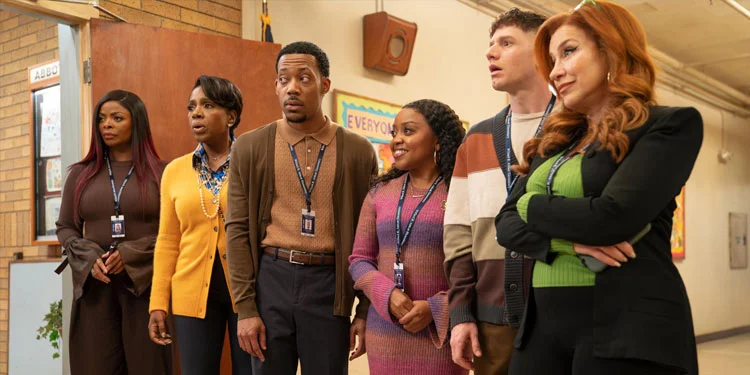 Na imagem, da esquerda para a direita, há uma mulher negra de cabelo longo e liso, vestindo uma blusa marrom, uma calça de tom escuro e um crachá no pescoço. Ao seu lado, há uma mulher negra de cabelo curto e liso, vestindo uma camisa amarela, um colar de pérolas e calças azul-escura. Em seguida, há um homem negro de cabelo curto vestindo um suéter e casaco marrom, com um crachá no pescoço, uma calça social azul e um cinto de couro. Próximo a ele, há uma mulher negra sorrindo com cabelos longos e cacheados, vestindo um vestido colorido, brincos dourados e um crachá no pescoço. Ao fim da imagem, há um homem branco de cabelo cacheado, suéter listrado colorido e crachá no pescoço, e, ao seu lado, uma mulher branca de cabelo ruivo e longo, usando um casaco preto, uma blusa verde e calça preta. 