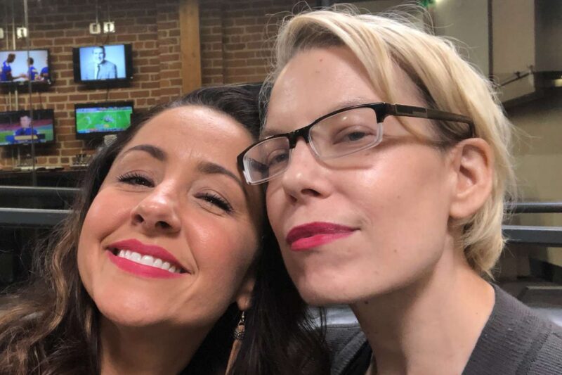 Selfie do Instagram de Nikki Boyer. À esquerda, Nikki, de cabelos mais escuros e batom rosa sorri com a cabeça encostada em Molly, que usa óculos de grau e tem cabelos curtos e loiros e também sorri na foto.