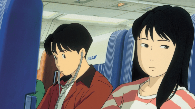 Cena da animação "Eu Posso Ouvir o Oceano", do Studio Ghibli. A imagem mostra os protagonistas Taku Morisaki, à esquerda, e Rikako Muto, à direita, sentados lado a lado dentro de um avião. Taku, de cabelo preto e jaqueta vermelha, olha para baixo com fones de ouvido. Rikako, de longos cabelos pretos e blusa listrada, olha para o lado com uma expressão pensativa. Os assentos do avião são azuis e o logo da companhia aérea ANA é visível.