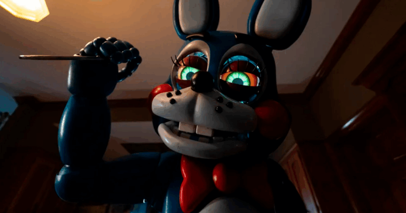 Cena de Five Nights at Freddy’s 2. A cena mostra um boneco de Bonnie The Bunny, em tons de azul escuro e branco, ocupando o centro da imagem. O boneco tem um sorriso largo, revelando dentes quadrados, e olhos grandes e brilhantes com contornos coloridos em tons de verde, vermelho e amarelo. Ele usa uma gravata borboleta vermelha e bochechas vermelhas. O coelho segura um objeto fino e escuro com a mão direita, apontando-o para cima. O fundo é escuro e desfocado, com a sugestão de um interior doméstico, incluindo uma luz no teto e detalhes de madeira. A iluminação é dramática, com foco no coelho e sombras profundas em volta, criando uma atmosfera de suspense e mistério. A composição é em close-up, enfatizando a expressão do coelho e sua pose ameaçadora.