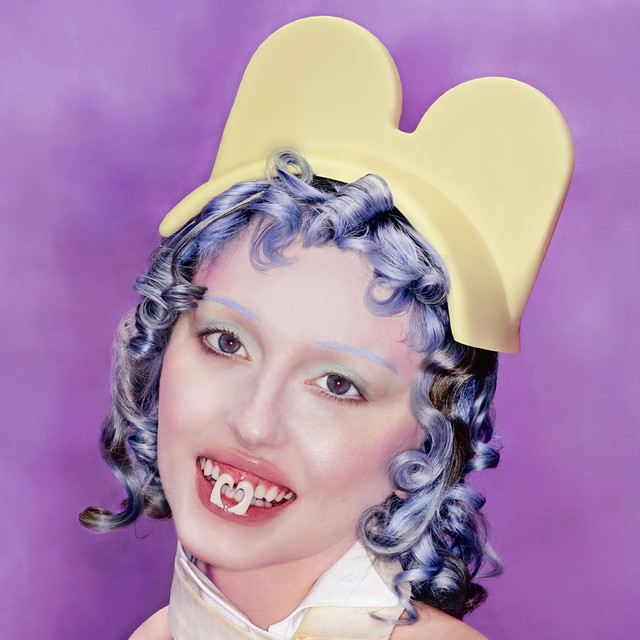 Ashnikko posa contra um fundo rosa liso. Ela é uma mulher branca de cabelo azul, que está preso e bagunçado e comporta um chapéu de tecido pied de poule preto e branco. Ela veste um corpete vermelho de cetim e uma faixa branca no busto com a inscrição Smoochie Girl em letras maiúsculas. Nas pernas, uma meia fina preta com manchas brancas. Sua expressão é distante e melancólica, com maquiagem marcada nos olhos e batom nude escuro