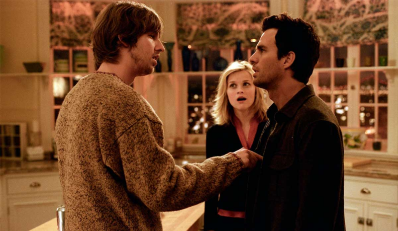 Cena do filme E Se Fosse Verdade. Em uma cozinha com armários brancos e iluminação quente, o personagem Darryl (Jon Heder), vestindo um suéter bege texturizado, aponta o dedo para o peito de David (Mark Ruffalo), que o encara de perto. Ao fundo, Elizabeth (Reese Witherspoon) observa a discussão com uma expressão de choque e a boca aberta.