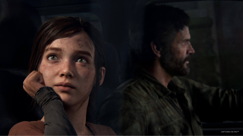 Cena de The Last of Us. Close-up do rosto de Ellie, uma jovem com sardas e cabelos castanhos, olhando para cima com uma expressão de esperança ou admiração. Ao fundo, levemente fora de foco, Joel, um homem mais velho, barbudo, com cabelo e barba preta, com algumas partes grisalhas, é visto de perfil dirigindo um veículo. A iluminação é suave, destacando o olhar de Ellie.