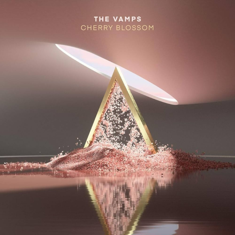 Capa do álbum Cherry Blossom do The Vamps. Um prisma dourado, posicionado no centro da imagem, ergue-se em um ambiente minimalista e sofisticado. O interior da forma de faces douradas e brilhantes jorra partículas rosadas, simulando pétalas, criando um efeito de cascata. A base do prisma se mistura com uma superfície espelhada que reflete a estrutura e os grãos finos, intensificando a simetria. Acima, uma abertura oval flutua, adicionando dinamismo à cena. O fundo é predominantemente em tons de rosa e cinza, com paredes e teto lisos e iluminação suave e uniforme, realçando o brilho do ouro e a delicadeza das partículas.