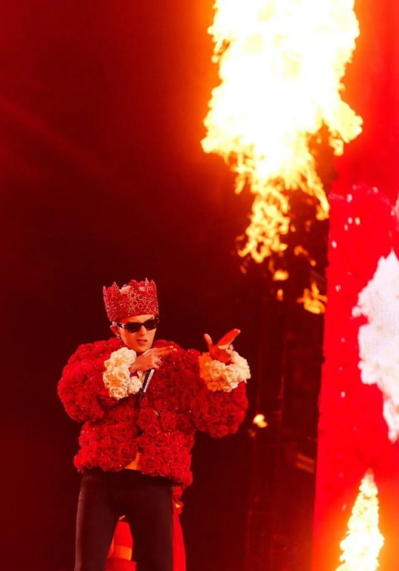 G-DRAGON performando em um dos shows da sua turnê Übermensch. Fotografia retangular, ao fundo vemos desfocado um efeito de fogo e um telão de seu show. G-DRAGON está ao centro da fotografia, vestindo uma jaqueta de rosas vermelhas e rosas brancas nos punhos, em sua cabeça uma coroa vermelha. Ele usa óculos de sol e apresenta uma expressão confiante enquanto aponta para frente com as mãos quase em de arma. 