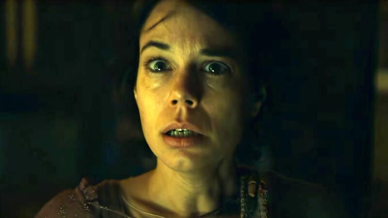 Cena do filme Maldição da Múmia Na imagem, a personagem Larissa Cannon está em primeiro plano, com expressão assustada: olhos arregalados e lábios abertos. O fundo está escuro. Ela é uma mulher espanhola, na faixa dos 40 anos, de pele clara e cabelos curtos escuros. 