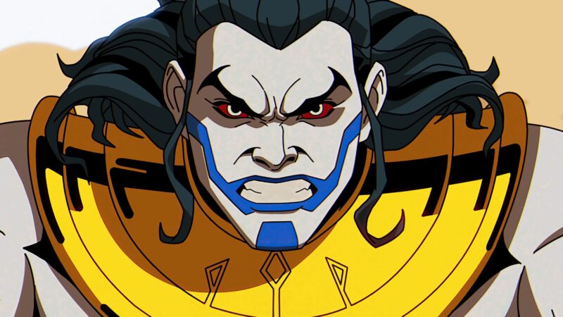 Cena de X-Men ‘97Na imagem, o personagem Apocalipse, na juventude, está com expressão de raiva, de testa franzida e dentes apertados. Ele possui pele branca, olhos vermelhos, cabelos escuros e longos e uma marca azul que desenha sua boca e seu queijo. Ele usa um colar egipcío na cor dourada. 