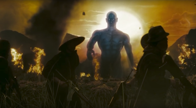 Cena do filme WatchmenNa imagem, o personagem Dr. Manhattan, um ser de pele na cor azul, careca e sem usar roupas, está andando em direção aos vietnamitas, que vestem roupas militares e um chapéu pontudo de palha. Manhattan está levantando a mão, pronto para atacá-los. Ao fundo, o sol está grande e à esquerda há uma grande fumaça preta. O cenário é de um campo com fogo nele.